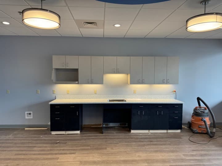 Office break-room kitchenette finish with recessed cans across the ceiling and two large drum pendant fixtures over the counter.