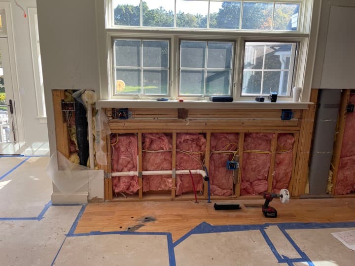 Mid-renovation interior with fresh window install and rough-in receptacles in the stud bays below the windowsill.